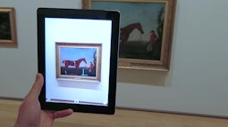 A person looks at an old painting of a horse through an iPad's camera.