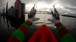A POV showing Freddy Kruger-esque hands reaching out while in a kayak in a large harbour.
