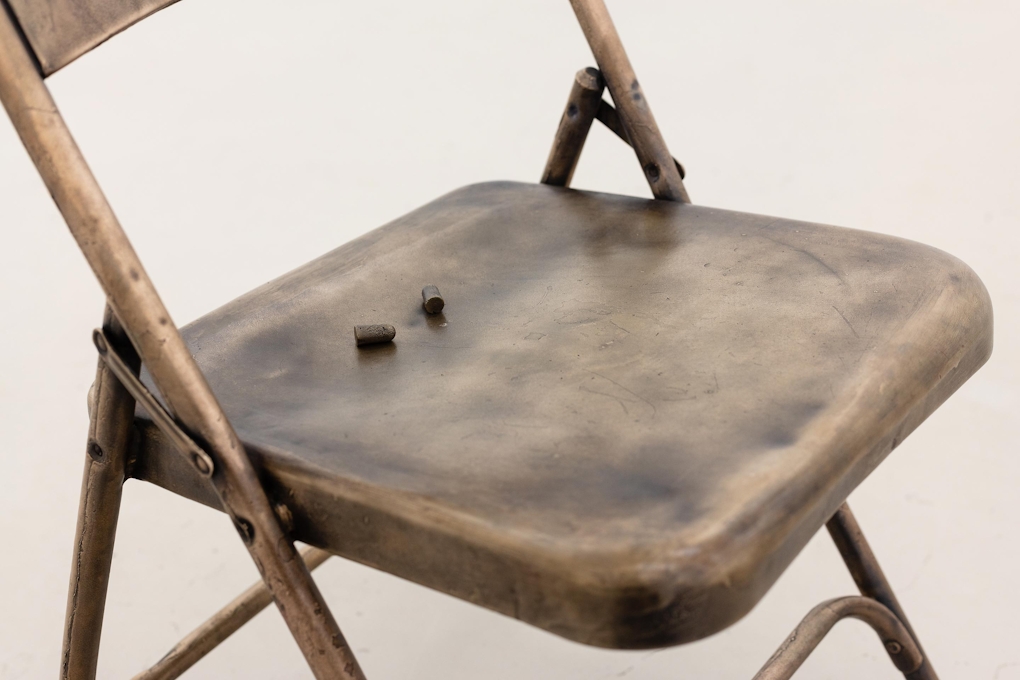 A metal chair with small metal earplugs sitting on top