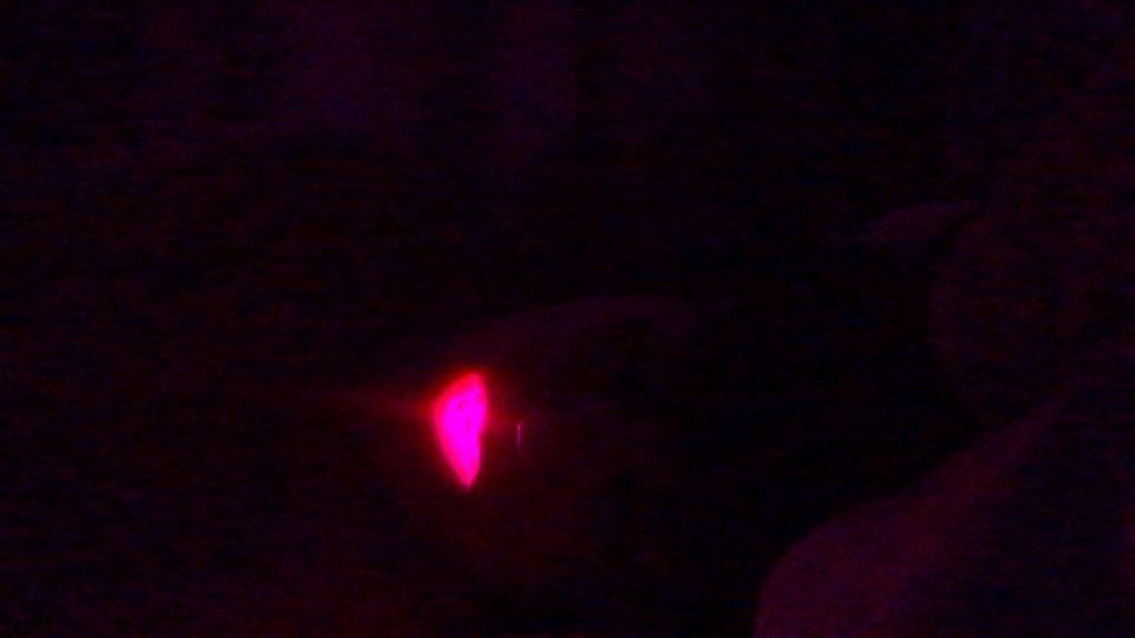 A very darkly lit image of a reclining figure, the mouth glows pink