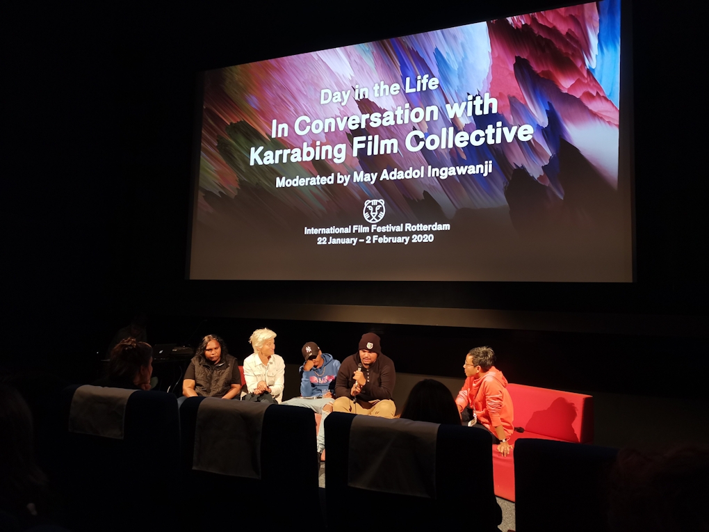 Five people sit on a panel underneath a screen that says “A day in the life, in conversation with Karrabing From Collective”