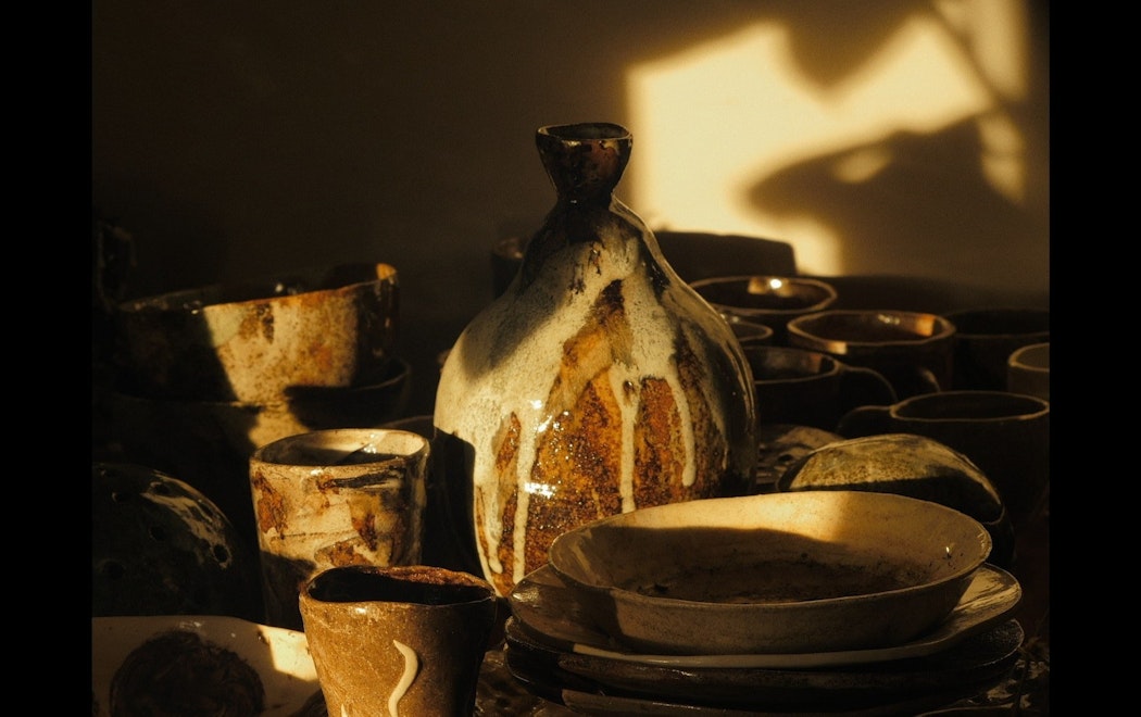 Late afternoon shadows across a series of clay vessels and plates