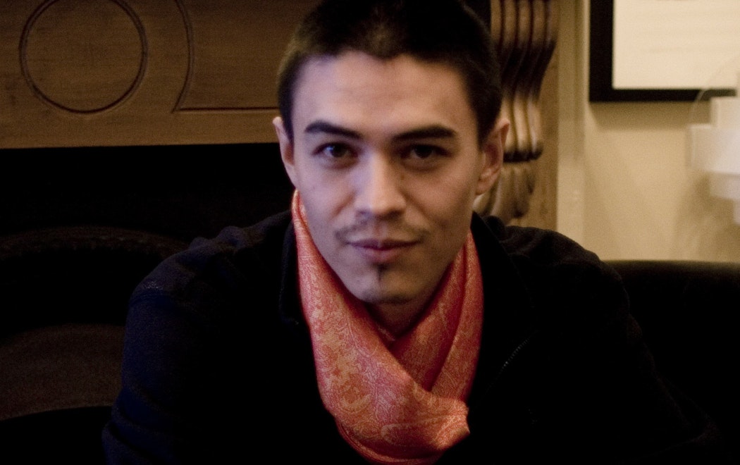 A person sitting in a chair with a orange scarf tied around their neck.