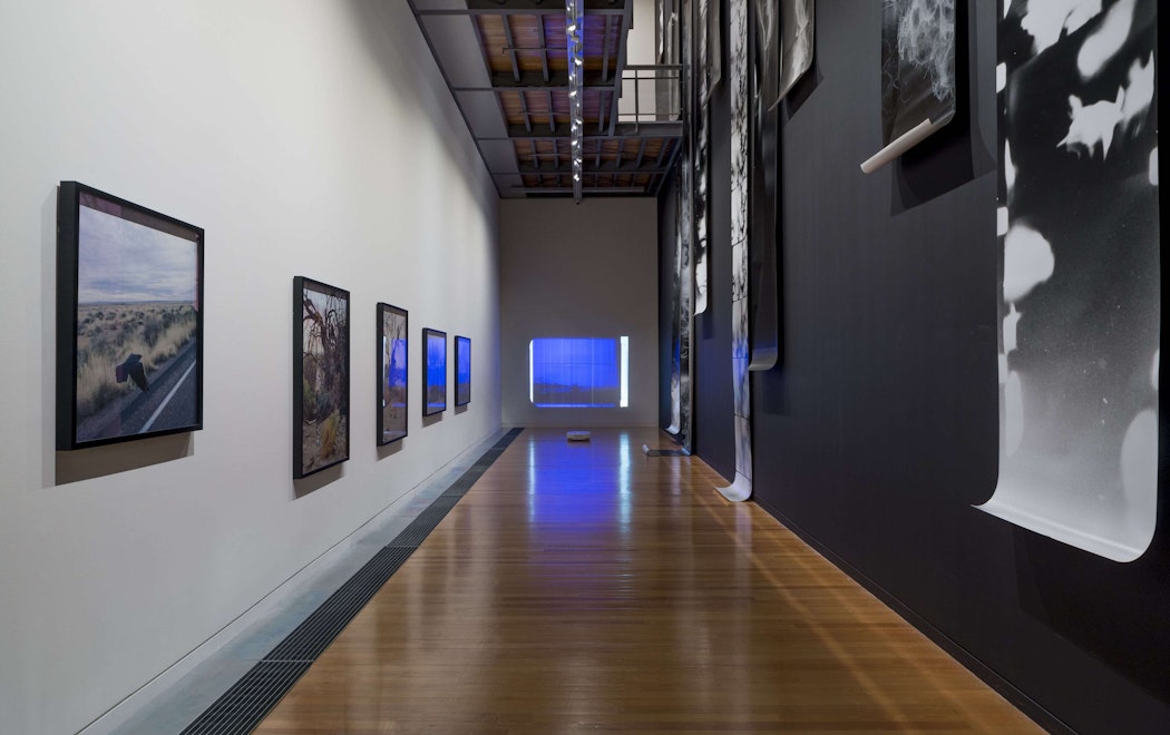 A long hallway-like gallery has framed images and long photographs displayed