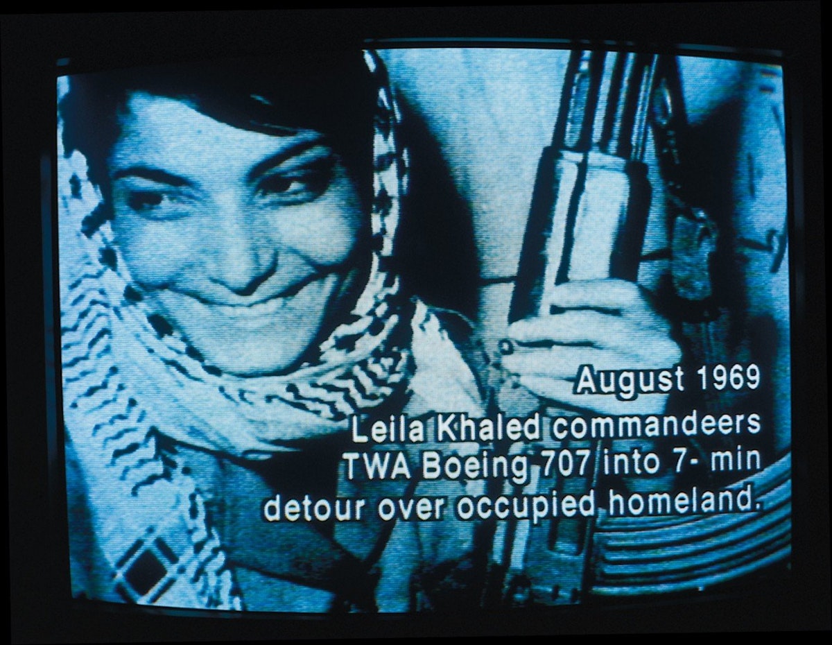 A woman is smiling, holding a gun on a grainy tv. Text on top of the images reads, "August 1969. Leila Khled commandeers TWA Boeing 7070 into 7-min detour over occupied homeland."