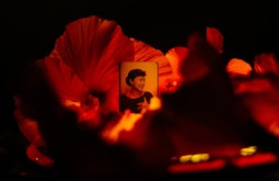 A portrait photograph of a Pasifika woman is set amidst orange-red hibiscus flowers