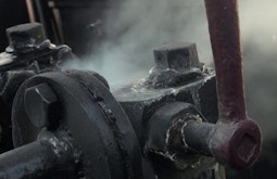 Steam plumbs out from an old engine made from steel.