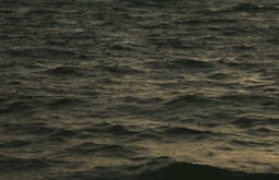 The sea at dusk, small caps appear on the waves.
