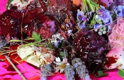 A collection of flowers and meat-like fluid and textures on a pink table.
