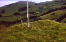 A large pole stands atop a rural hill.