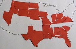 An outline map of the USA is partially filled in with red paper cut outs of some US States.