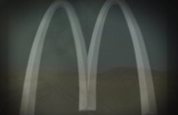 The McDonalds arches are overlaid on an image of a rural desert road and landscape.