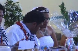 A bride and groom on their wedding day at the dining table.