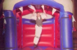 A grown adult bounces in a bouncy castle.