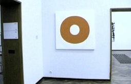 A painting in the shape of an O ring is hung in a gallery.