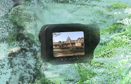 A digitally rendered camera showing a temple floats amongst a digital map of a landscape.