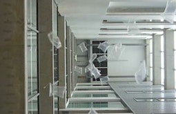 In an atrium of an office building inflated plastic bags fall from high above.