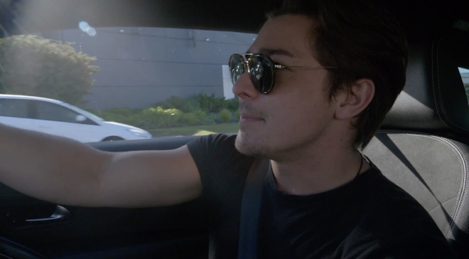 A young man wears dark sunglasses whilst driving
