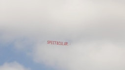 A large banner reading Spectacular flies behind a plane on a cloudy day.