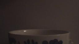 A close up of a mug, a light is reflected in the porcelain.