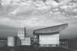 A black and white image of a concrete building with a sloped roof.