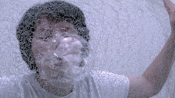 A person blows bubbles through a net.