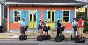 A small tour group of people on electric segways are assembled in front of a brightly coloured cafe in the Tremé district of New Orleans.