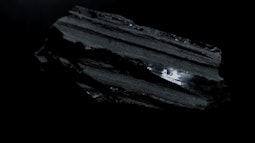 A dark glossy rock spins in a black void.