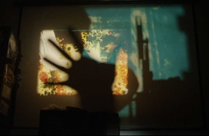 An analogue projection is being displayed on a wall. An out of focus hand is in front of the projection image obscuring it slightly.