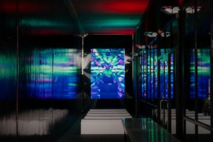 Looking down a shiny black hallway to see a colourful video projection