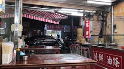 An empty restaurant in Taipei, there are chopsticks and condiments on each table. A glossy black car drives past.