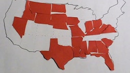 An outline map of the USA is partially filled in with red paper cut outs of some US States.
