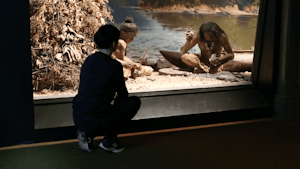 Ana squats down in a museum to haze upon a racist exhibit of Māori people in a museum