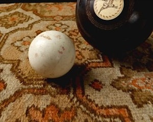 A magic 8-ball and a white pool ball sit on 70s patterned carpet