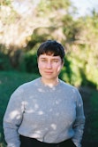 A profile image of a woman with a blurred garden background