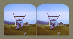 Two similar images of a weather measuring station on a mountain top have been pushed over and graffitied. Both photos have rounded edges at the top of the image and are backed by a beige green solid colour background.
