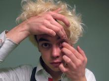 A person looks into the mirror while putting a contact lens in.