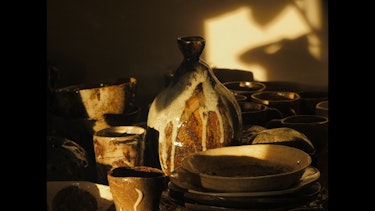 Late afternoon shadows across a series of clay vessels and plates