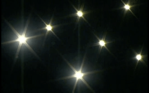 7 bright lights create star shapes in the dark sky