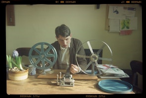 A person is inspecting a reel of film in a sunny room