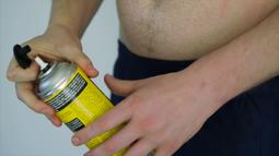 A topless person opens a can of expanding foam.