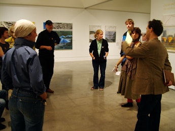A group of people stand in a gallery having a discussion.
