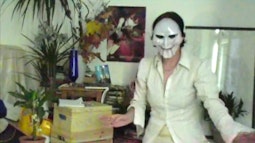 A person stands in a living room wearing a Billy the puppet mask.