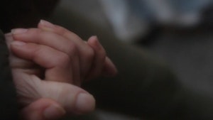 A close up of two people holding hands with a blurred background and dreamlike feel