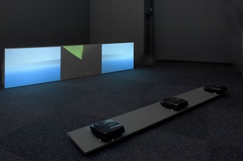Three images projected on to screens at floor height, the images show sky and other landscape