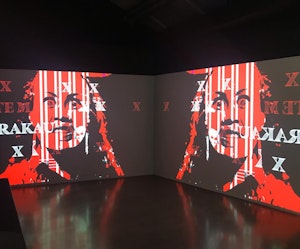 Jamies Berry Installation view of double-channel video work featuring black and red figure with the text “RAKAU” overlaid.