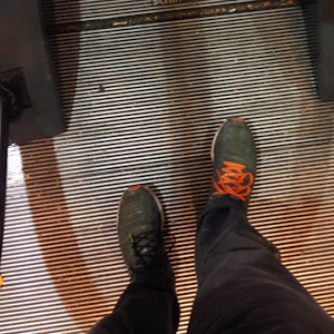 A view of green shoes with bright orange laces about to board an escalator