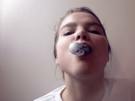 Niamph tilts her head back with a huge piece of bubble of grey gum coming out of her mouth