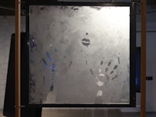 A steamy window in a wooden frame. There are two hand prints in the steam and a pair of lips.