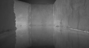 A black and white image of walls surrounding a glassy surface.